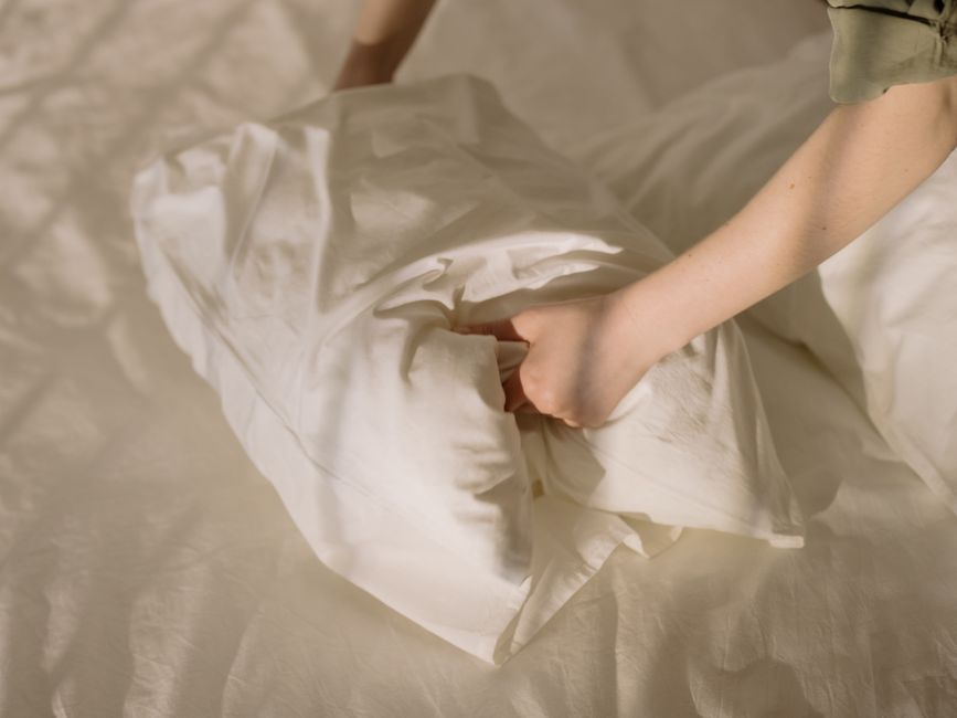 Close-up of clean white linens in a cozy bedroom setting, emphasizing comfort and cleanliness.